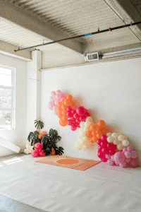 Balloon garland installation curving across a white studio wall