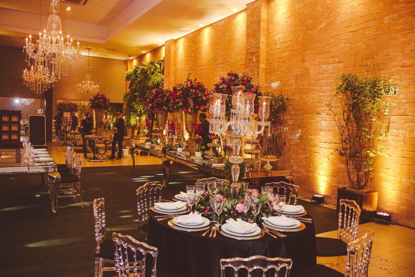 A banquet hall dressed for a gala, with chandeliers, florals and set tables